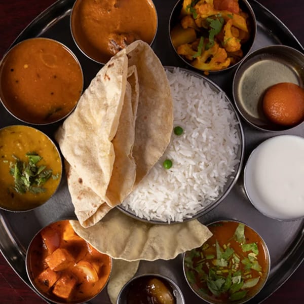 A Udupi Cafe thali with various Indian dishes, including rice, curries, bread, and dessert.