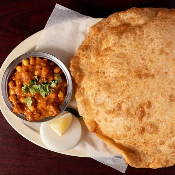 Chana Bhatura from Udupi Cafe, featuring a large fried bread and a bowl of chickpea curry.
